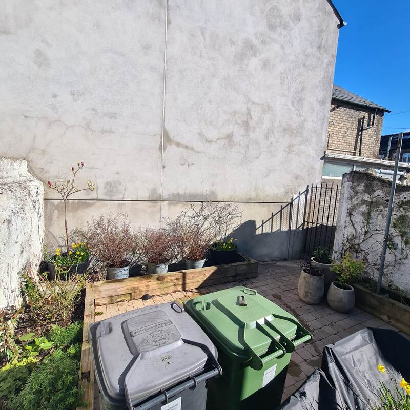 Same courtyard corner before, showing the bin storage area