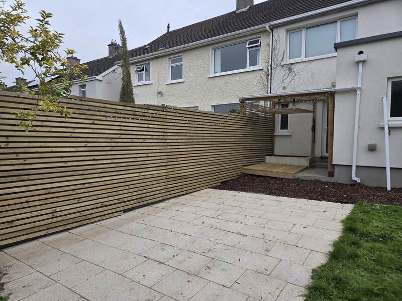 Finished slatted timber fencing and pergola along a rear garden