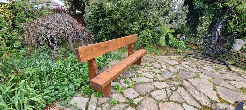 Solid timber garden bench on a stone patio